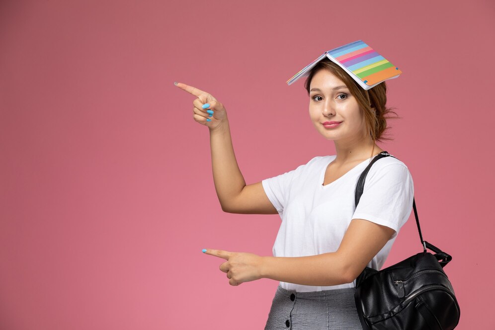 front-view-young-female-student-white-t-shirt-with-copybook-smile-pink-background-lesson-university-college-study-book_140725-35094