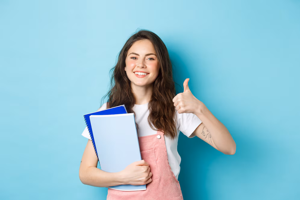 young-woman-attend-courses-girl-student-studying-holding-notebooks-showing-thumb-up-approval-recommending-company-standing-blue-background_1258-70145